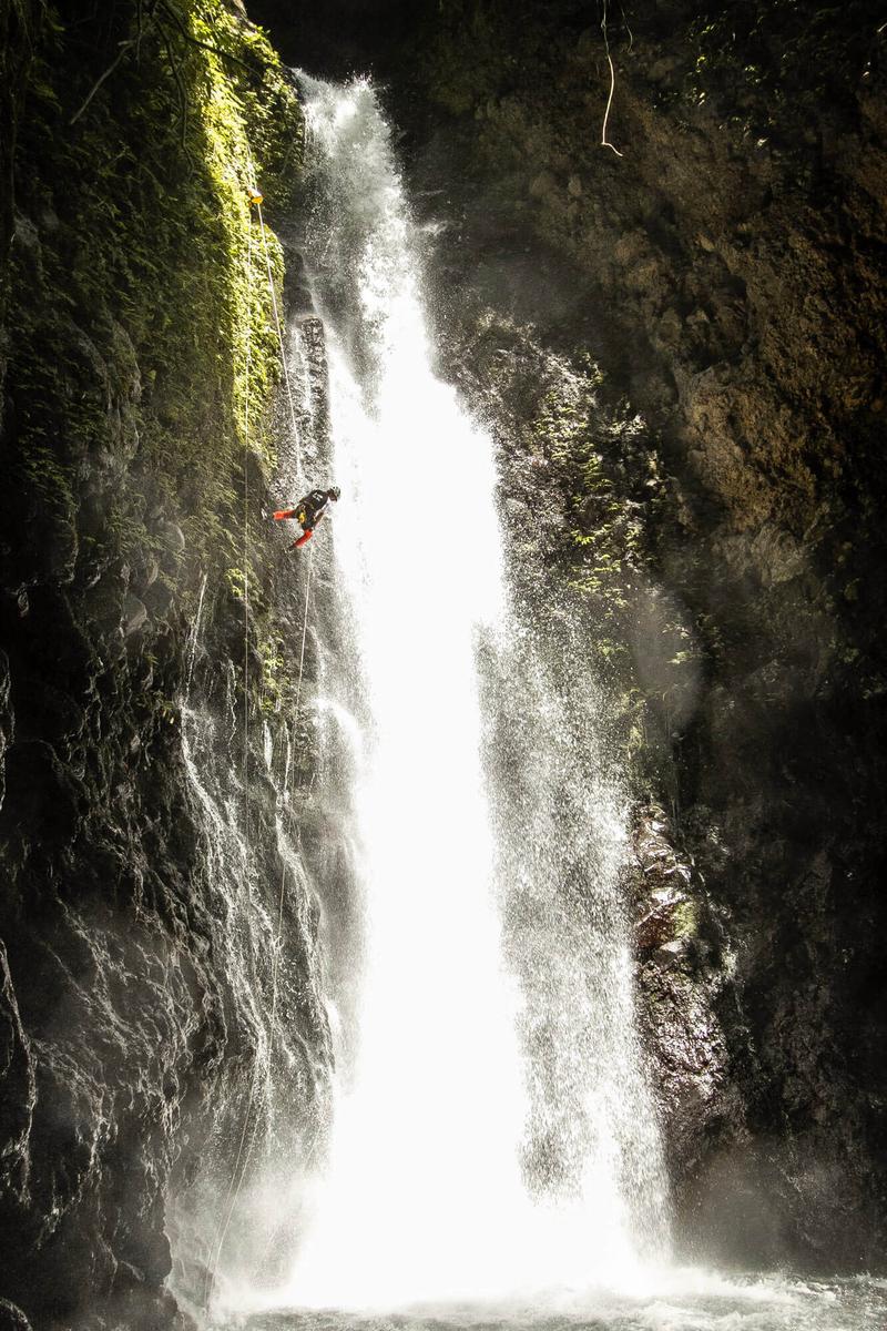 A canyoneer rappels down a waterfall in Bali.